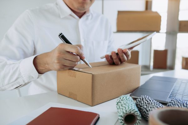 business teenager is looking on tablet and writing a customer address contact to deliver